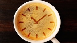 Cup of coffee with clock face imprint in coffee